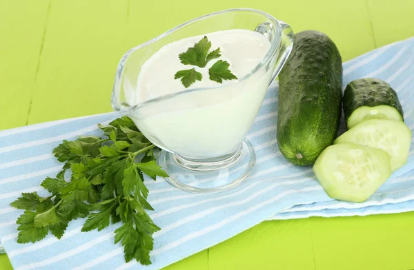 Komkommer yoghurt in glazen kom, op kleur servet, op houten achtergrond — Stockfoto