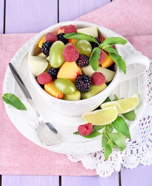 Salada de frutas em xícara em guardanapo em mesa de madeira — Fotografia de Stock