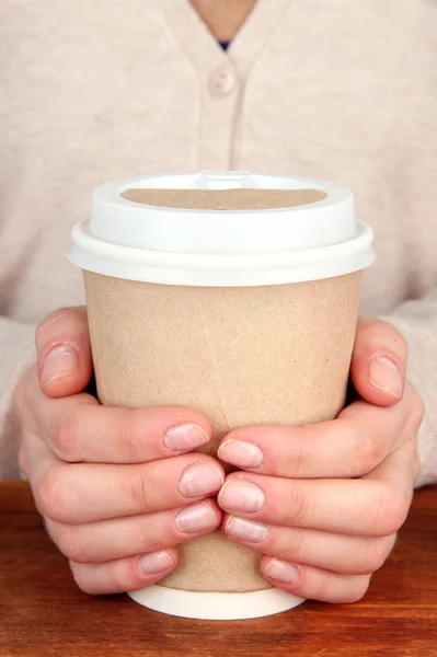 Hot drink in paper cup in hands — Stock Photo, Image