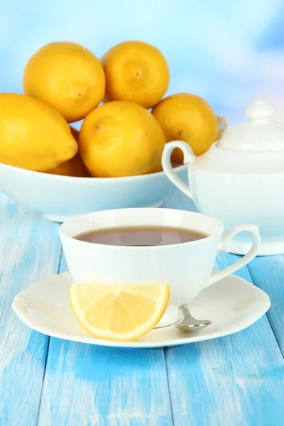 Kopje thee met citroen op tafel op blauwe achtergrond — Stockfoto