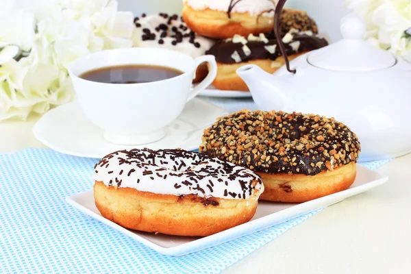 Сладкие пончики с чашкой чая на столе крупным планом — стоковое фото