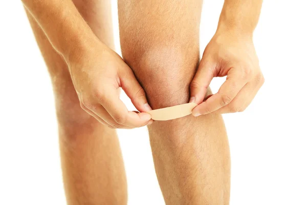 Ung man med självhäftande bandage på knä, isolerad på vit — Stockfoto