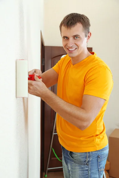 Jovem homem pinta parede em novo apartamento — Fotografia de Stock