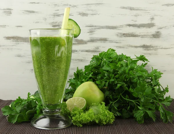 Óculos de suco de legumes verde no tapete de bambu no fundo de madeira — Fotografia de Stock