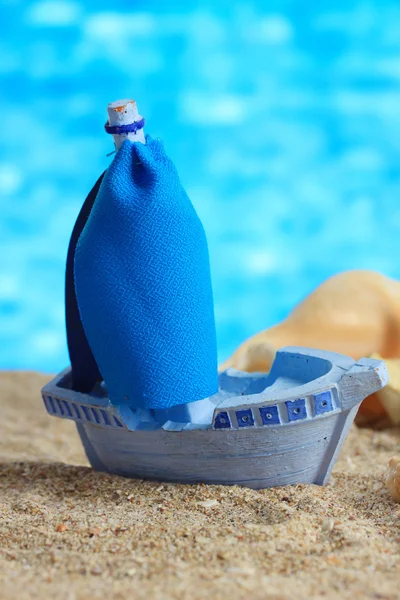 Bateau jouet bleu sur sable, sur fond bleu — Photo