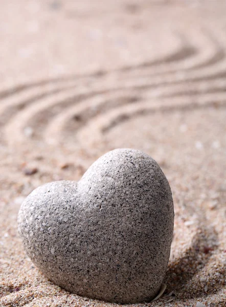 Pietra zen grigia a forma di cuore, su sfondo di sabbia — Foto Stock