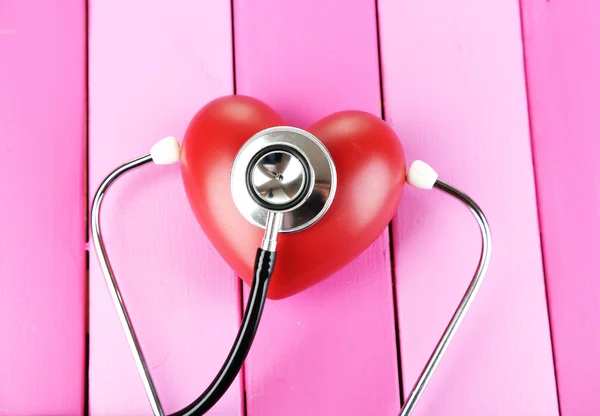 Stethoscope and heart on wooden table close-up — Stock Photo, Image