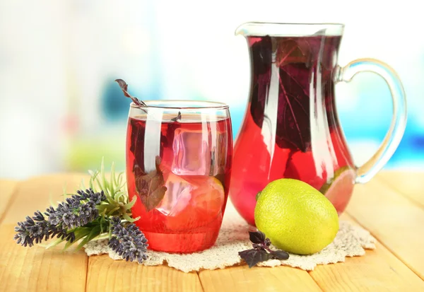 Red basil lemonade in jug and glass, on wooden table, on bright background — Stock Photo, Image