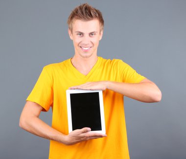 gri zemin üzerine tablet ile yakışıklı bir genç adam