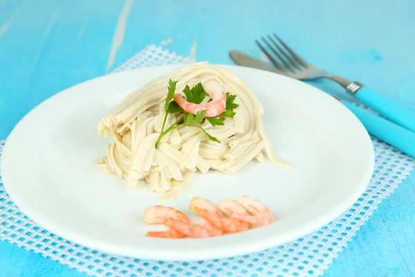 Pasta with shrimps on white plate, on wooden background — Stock Photo, Image