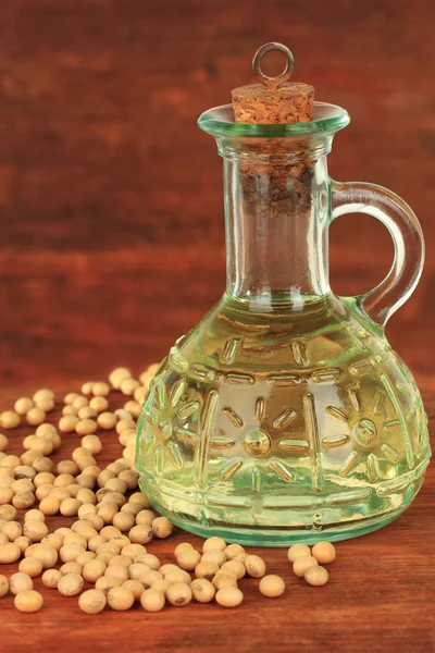 Soy beans and oil on wooden background — Stockfoto