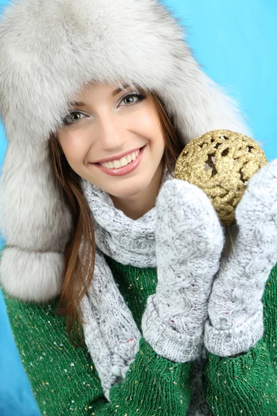 Menina sorridente bonita com bola de Natal no fundo azul — Fotografia de Stock