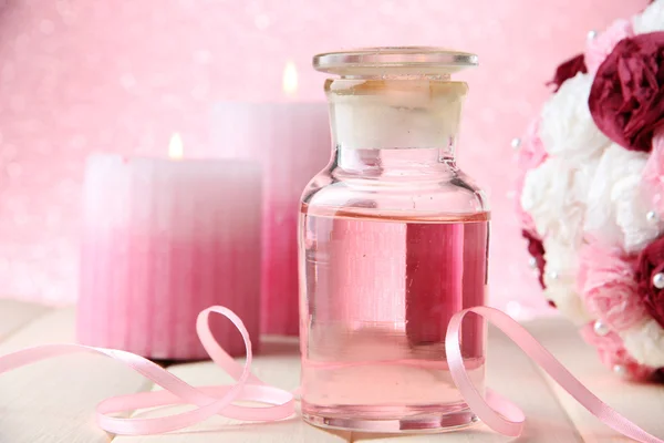 Bouteille en verre avec essence de couleur, sur fond rose — Photo