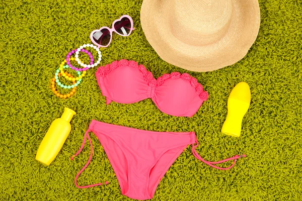 Swimsuit and beach items on green background — Stock Photo, Image