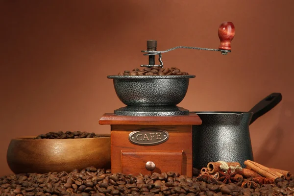Coffee grinder, turk and coffee beans on brown background — Stock Photo, Image