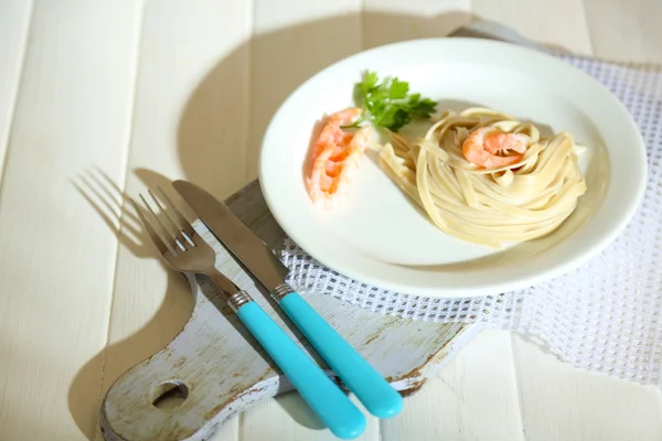 Pasta con gambas sobre plato blanco, sobre fondo de madera — Foto de Stock