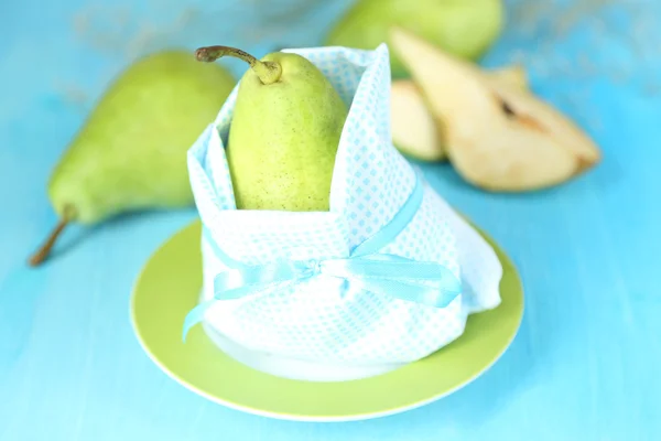 Pear in napkin on plate on wooden table close-up — Stock Photo, Image