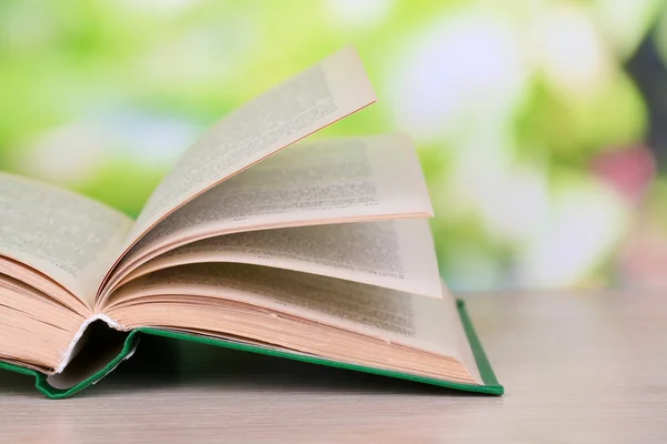 Livro aberto sobre mesa de madeira sobre fundo natural — Fotografia de Stock