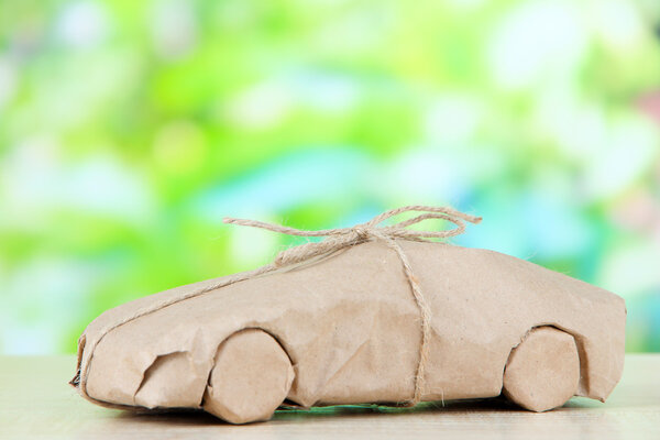 Автомобиль, завернутый в бумагу из крафта, на фоне природы
