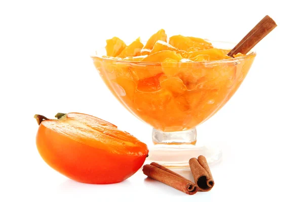 Half persimmon with jam in glass saucer and cinnamon isolated on white — Stock Photo, Image