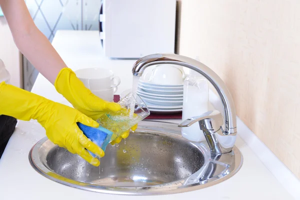 Fermer les mains de la femme qui lave la vaisselle dans la cuisine — Photo