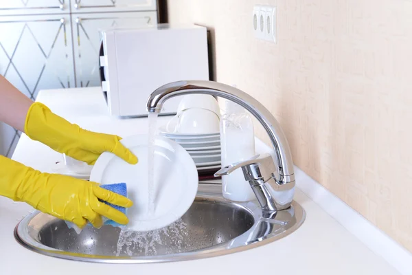 Fermer les mains de la femme qui lave la vaisselle dans la cuisine — Photo