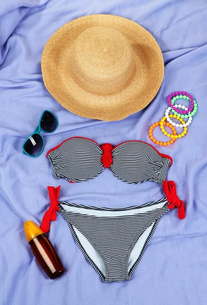 Swimsuit and beach items on purple background — Stock Photo, Image