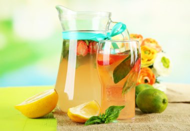 fesleğen limonata sürahi ve parlak zemin üzerine ahşap masa üzerinde cam çilek ile