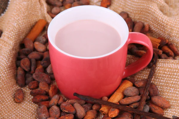 Cocoa drink and cocoa beans on sackcloth background — Stock Photo, Image