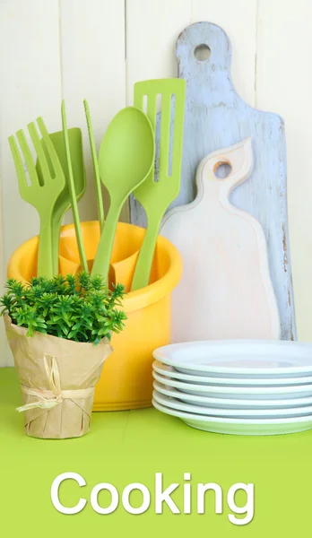 Utensilios de cocina de plástico en taza sobre mesa de madera —  Fotos de Stock