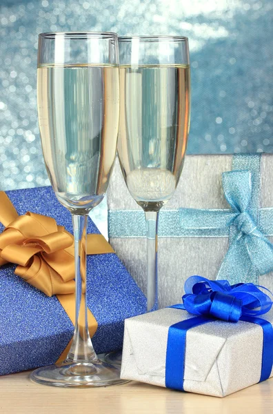 Glasses of champagne with gift boxes on shiny background — Stock Photo, Image