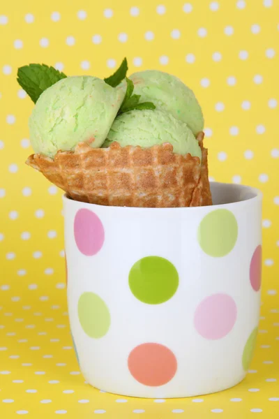 Sorvete verde apetitoso com cone de waffle na xícara no fundo de bolinhas — Fotografia de Stock