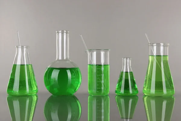 Reagenzgläser mit grüner Flüssigkeit auf grauem Hintergrund — Stockfoto