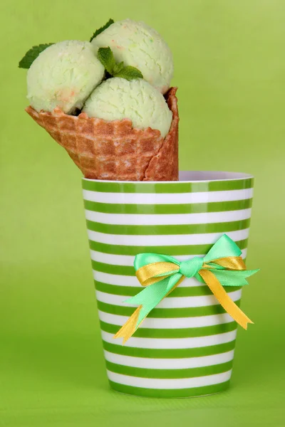 Appetizing pink ice cream with waffle cone in cup on green background — Stock Photo, Image