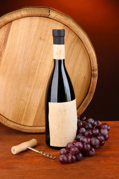 Composition of corkscrew and bottle of wine, grape, wooden barrel on wooden table on dark background — Stock Photo, Image