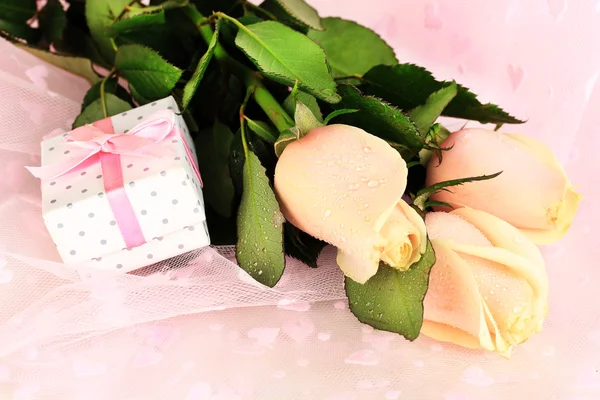 Rosas bonitas e presente em pano rosa, close-up — Fotografia de Stock