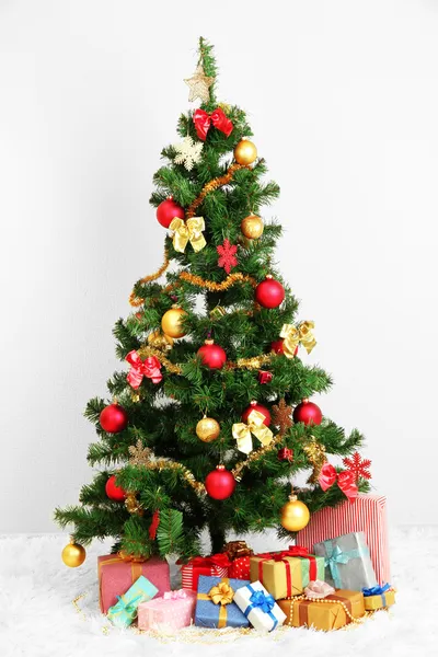 Geschmückter Weihnachtsbaum mit Geschenken auf grauem Wandhintergrund — Stockfoto