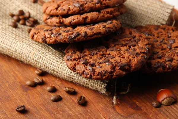 Homemade cookies with sesame seeds, chocolate, on wooden table, on sackcloth background — Stock Photo, Image