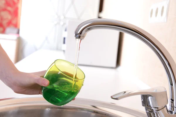 Hand hält Glas Wasser aus Küchenarmatur gegossen — Stockfoto