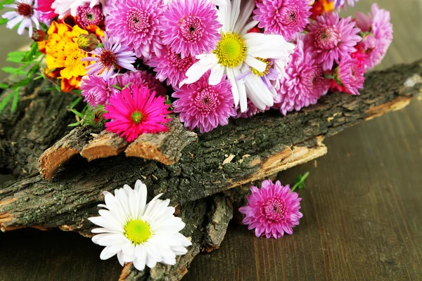 Wildflowers and tree bark on wooden table — Stock Photo, Image