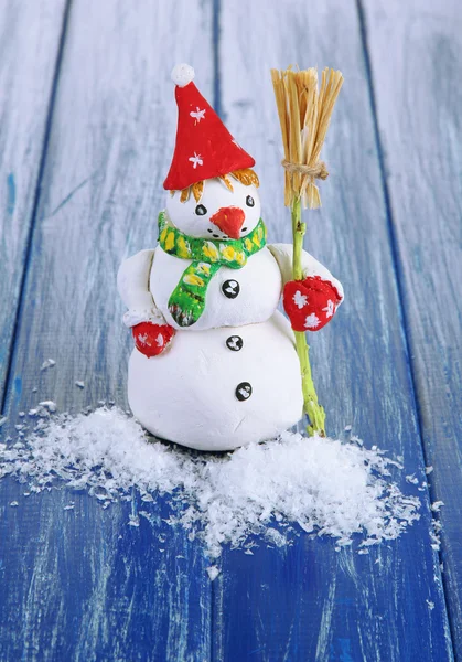 Schöner Schneemann auf blauem Holzhintergrund — Stockfoto