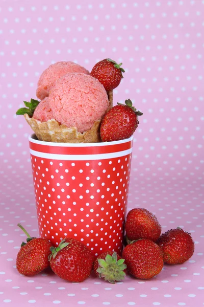 Appetitliche rosa Eis mit Waffelkegel in Tasse auf gepunktetem Hintergrund — Stockfoto