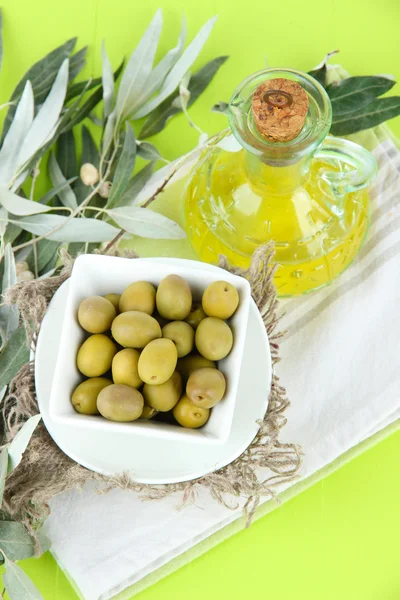 Olives in bowl with branch on sackcloth on wooden board on table — Stock Photo, Image