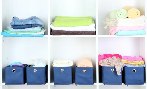 Modrý textilní boxy s ručníky a šaty v bílé police — Stock fotografie