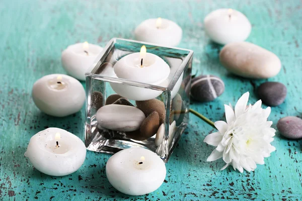 Jarrón decorativo con velas, agua y piedras sobre mesa de madera —  Fotos de Stock