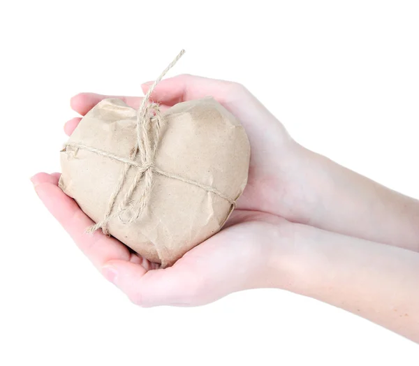 Mains de femme tenant un cœur enveloppé dans du papier kraft brun, isolé sur du blanc — Photo