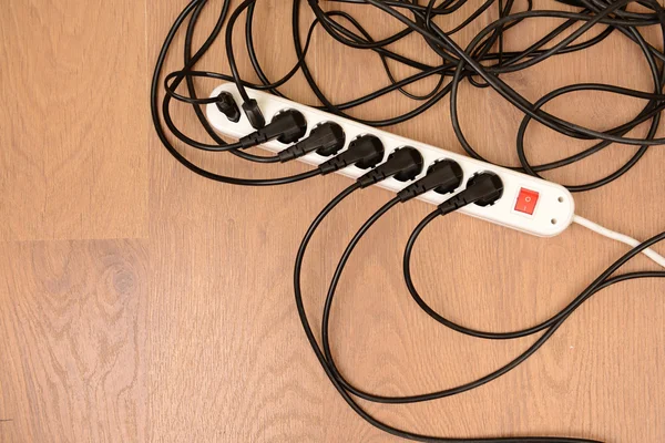 Overloaded power boards, on wooden floor background — Stock Photo, Image