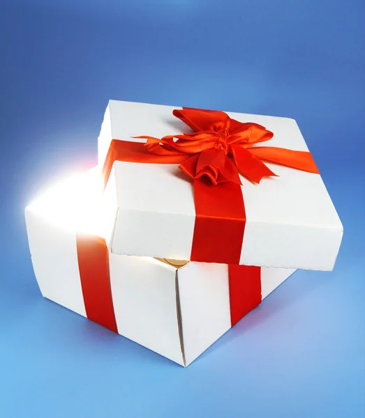 Caja de regalo con luz brillante sobre fondo azul — Foto de Stock