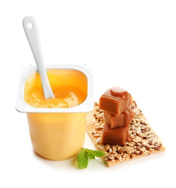 Sabroso yogur con trozos de fruta fresca, galletas y caramelos de caramelo aislados en blanco —  Fotos de Stock