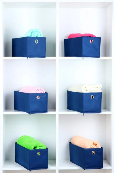 Сині текстильні коробки з рушниками на білих полицях — стокове фото